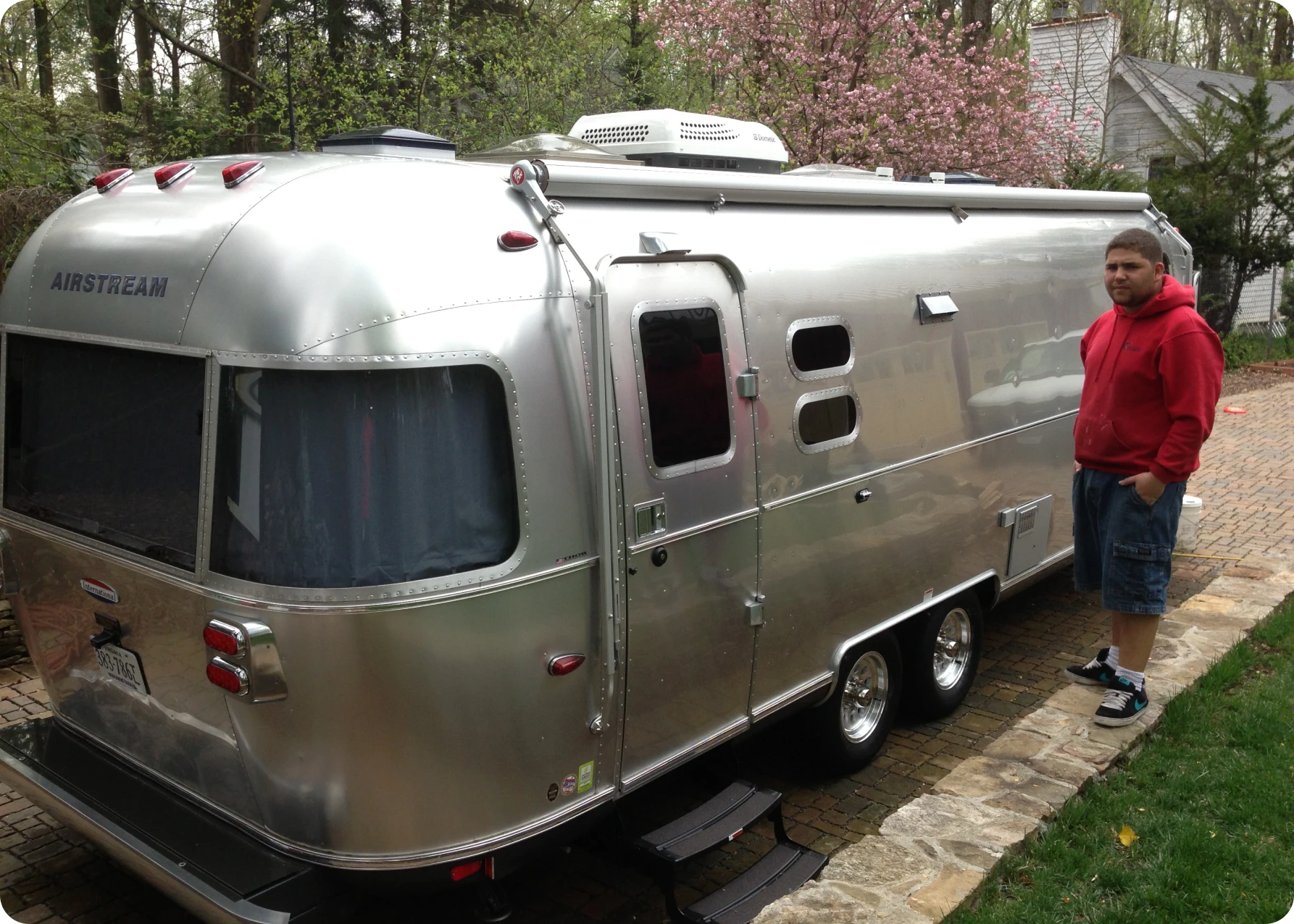 Person standing beside silver Airstream trailer