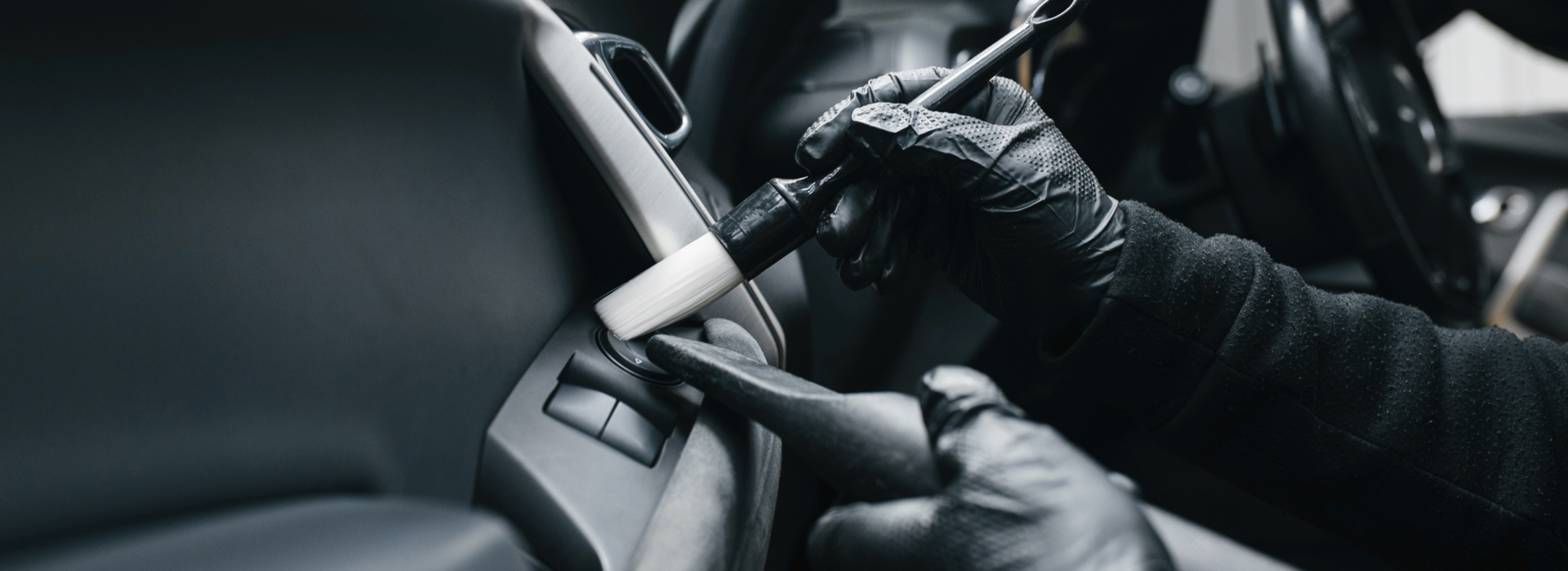 Gloved hands cleaning car interior with brush